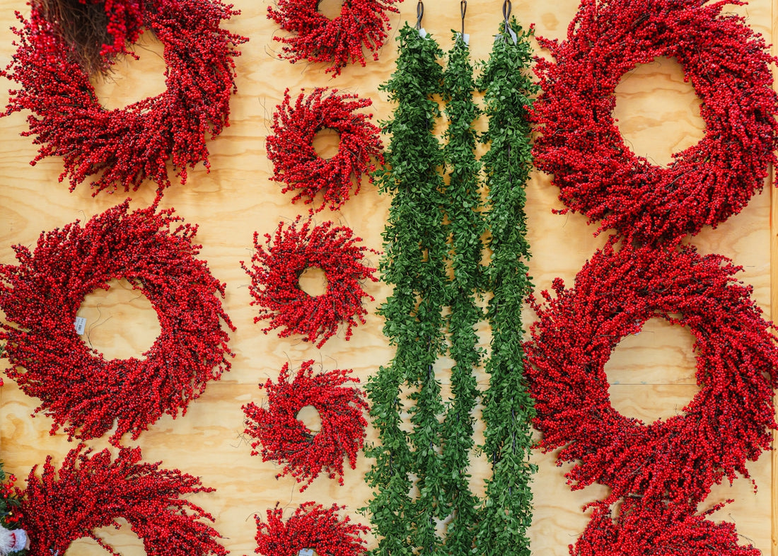 Assortment of red wreaths and green garlands displayed