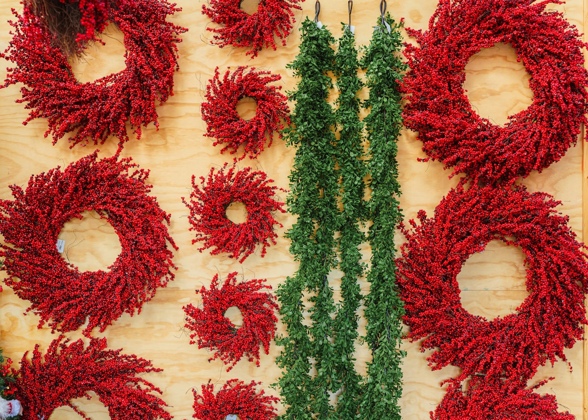 Assortment of red wreaths and green garlands displayed